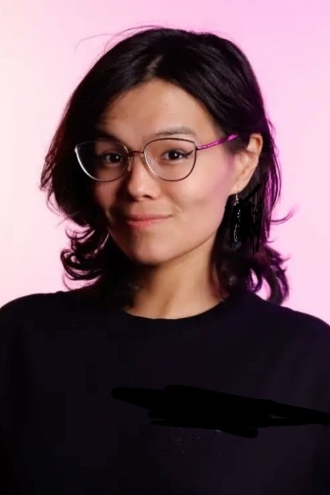 A half Korean half Italian/Irish girl with brown eyes smiling at the camera with dark hair coming down to her shoulders.